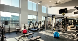 The Beacon fitness center with a wall of windows and ample equipment