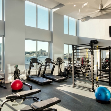 The Beacon fitness center with a wall of windows and ample equipment