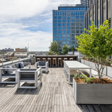 Exterior terrace with wood deck, landscaping, lounge sea, dining area, bar, and grills with views of Downtown New Orleans