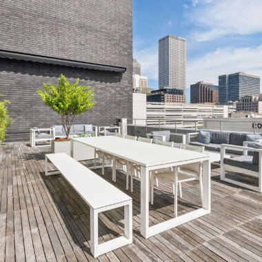 Exterior terrace with wood deck, landscaping, lounge sea, dining area, bar, and grills with views of Downtown New Orleans