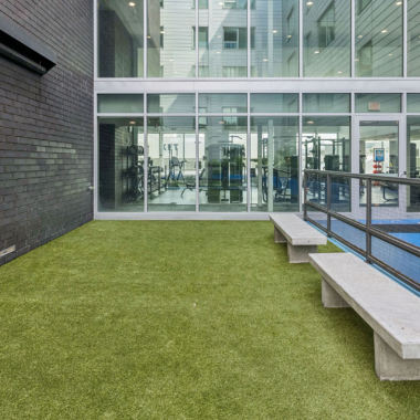 Fenced dog park with bench seating within interior courtyard