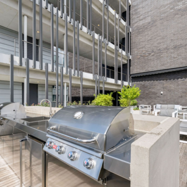 Exterior terrace with wood deck, landscaping, lounge sea, dining area, bar, and grills with views of Downtown New Orleans